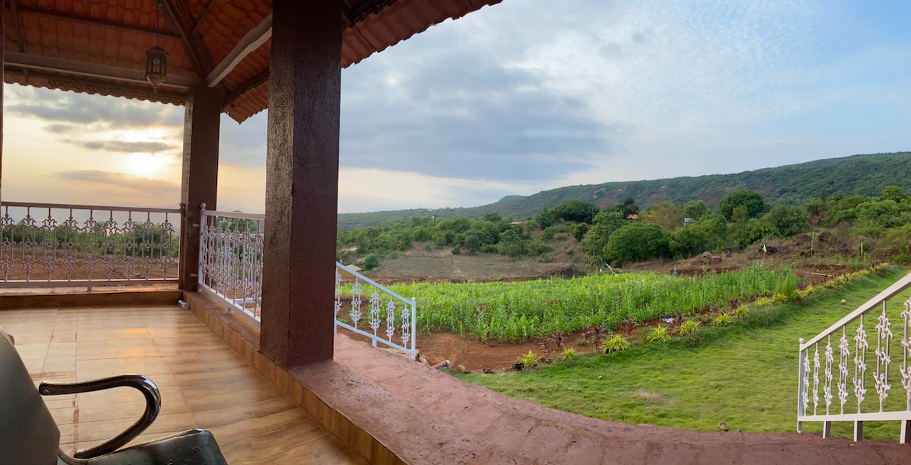 Sunset view from the veranda overlooking organic farmland and Sahyadri hills